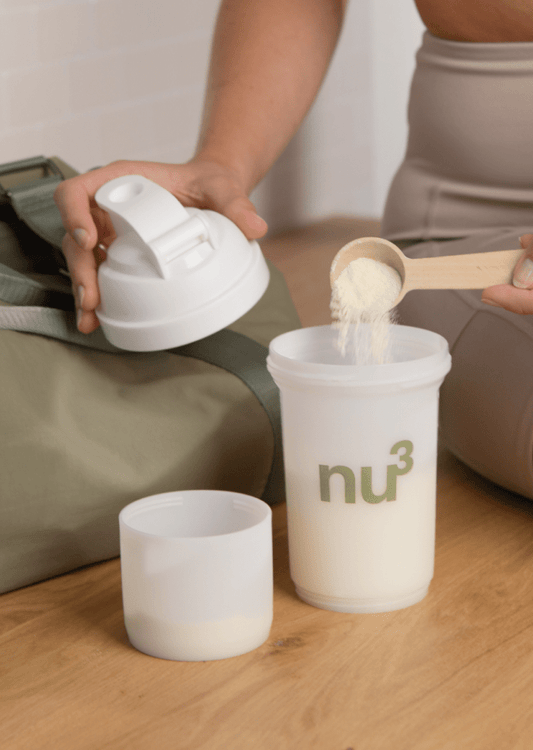 Frau füllt Shake-Pulver in Shaker