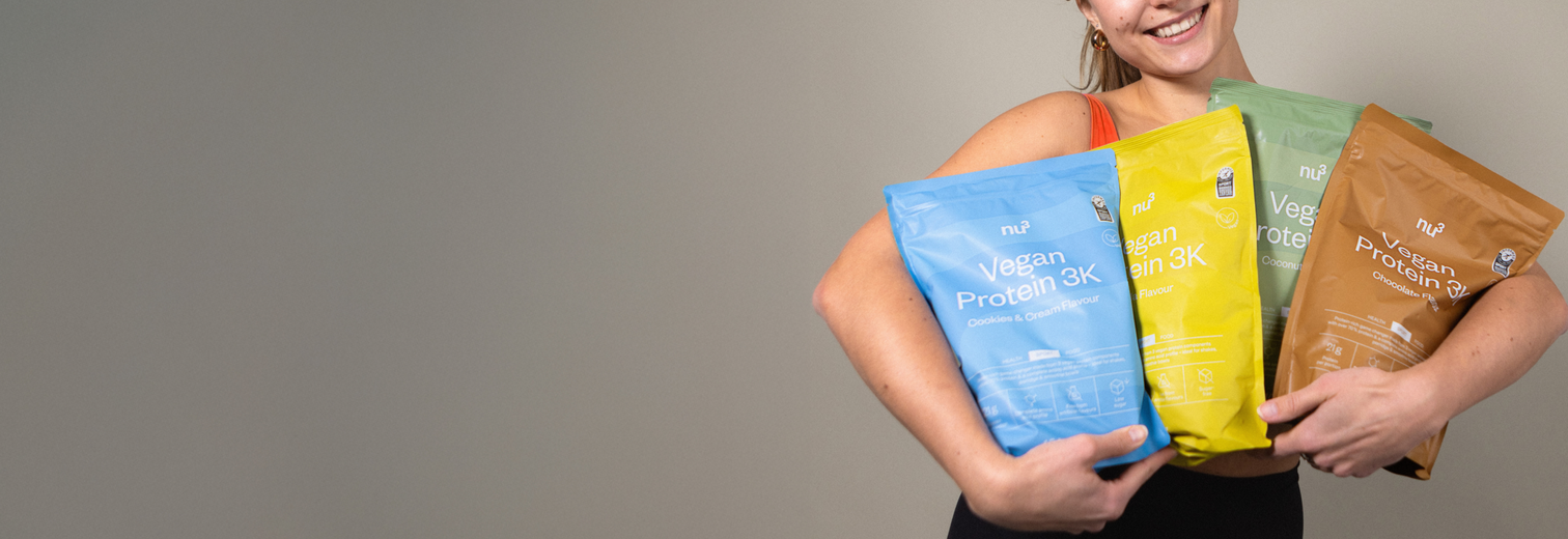 Femme souriante avec des paquets de nu3 Vegan Protein 3K