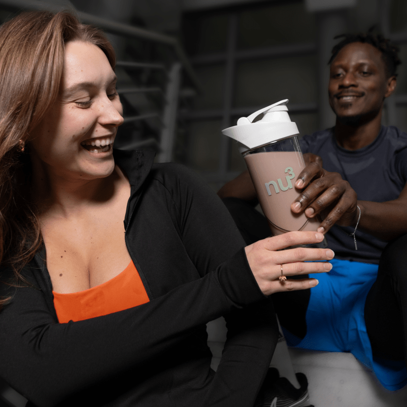 Sportlicher Mann reicht Shake an sportliche Frau