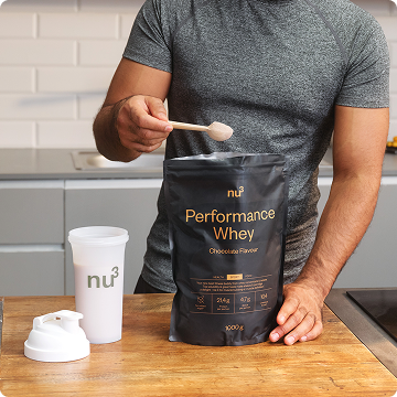 Un homme verse une cuillère de nu3 Performance Whey dans un shaker